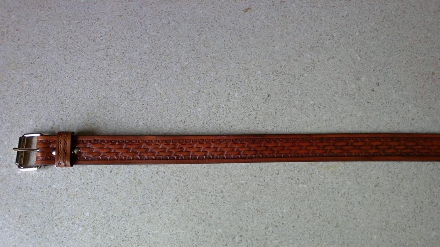 Brown leather belt with a silver buckle and repeating basketweave tooling