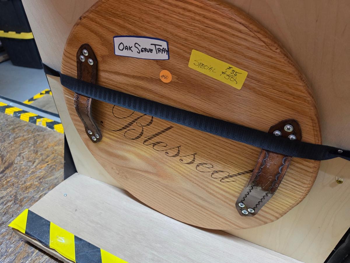 Wood grain and Blessed lettering on a round handled serving tray in Howard’s shop