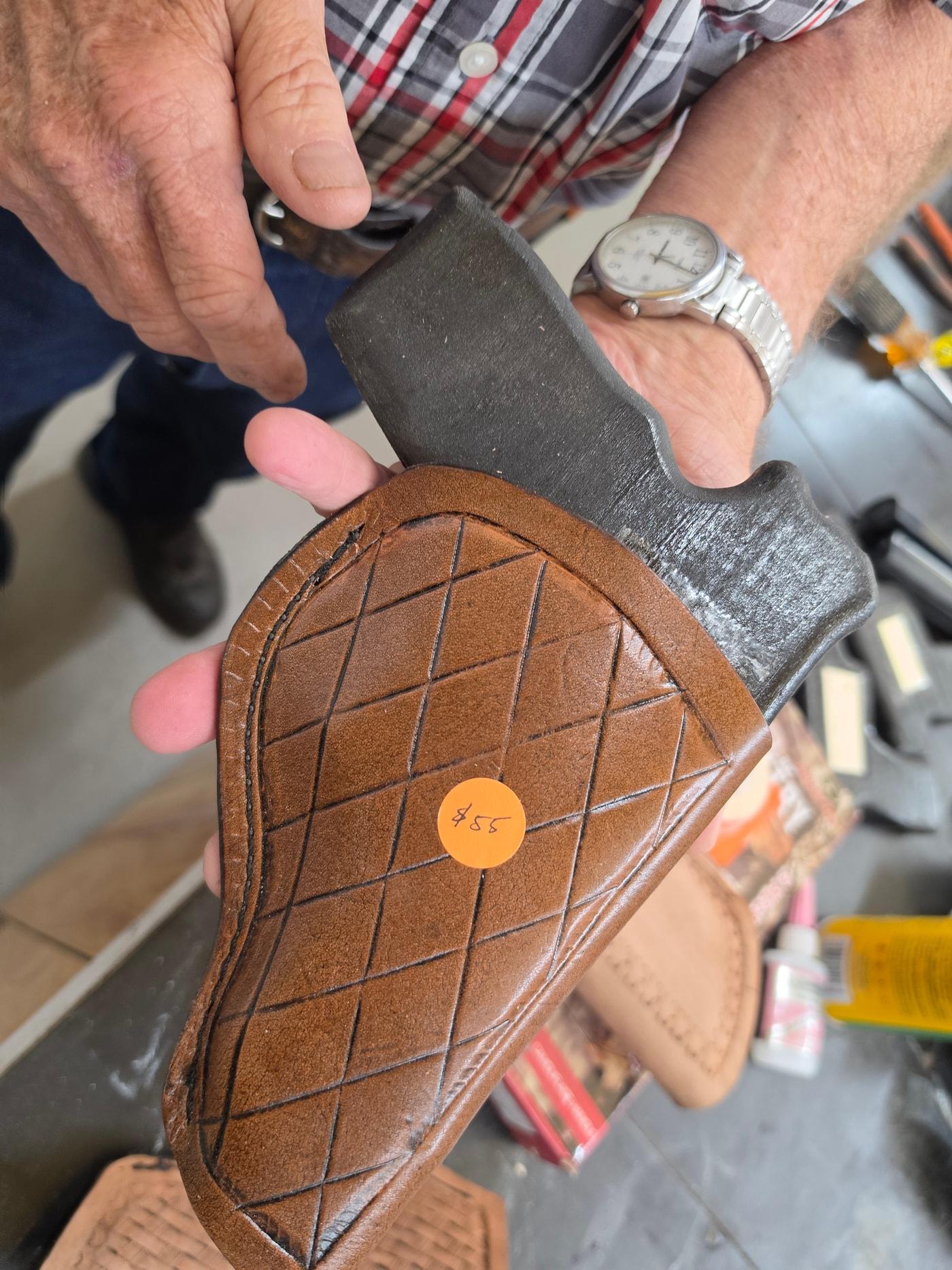 Hands holding a diamond-pattern leather holster, showing its stitched edge