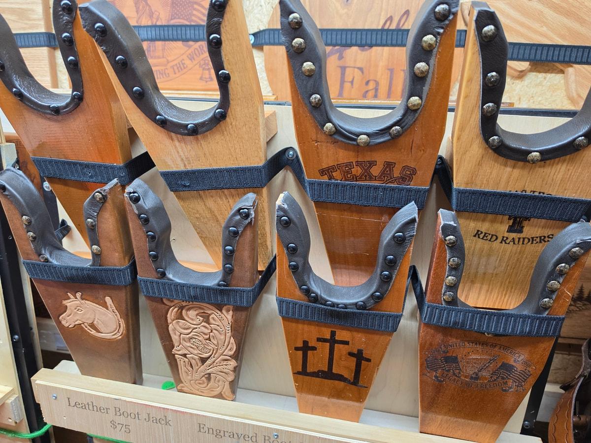 Leather bottle holders with floral, horse, and cross designs on the shop wall