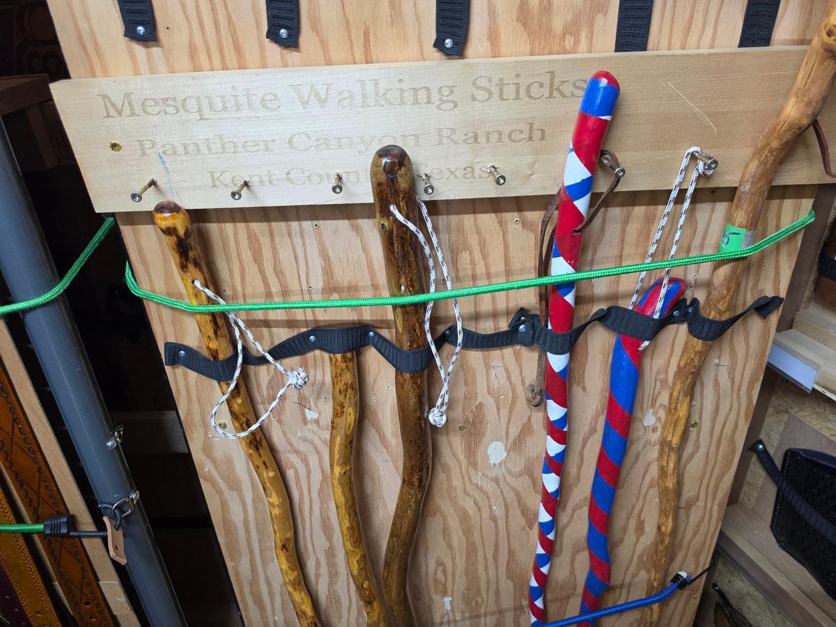 Several walking sticks with varied handles and finishes in a wooden shop rack